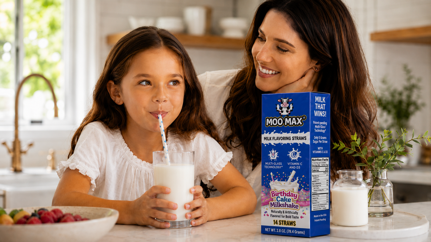Child drinking milk through a MooMax Milk Flavoring Straw with a parent nearby and a MooMax Birthday Cake Milk Flavoring Straws box on the kitchen counter.